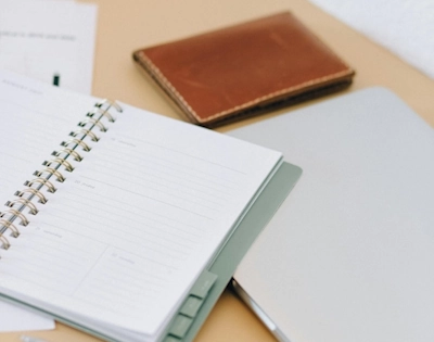 Photo représentant des carnets ouverts sur une table et un téléphone portable afin d'illustrer l'activité d'une assistante administratrive indépendante à Lambersart