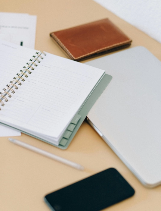 Photo représentant des carnets ouverts sur une table et un téléphone portable afin d'illustrer l'activité d'une assistante administratrive indépendante à Lambersart